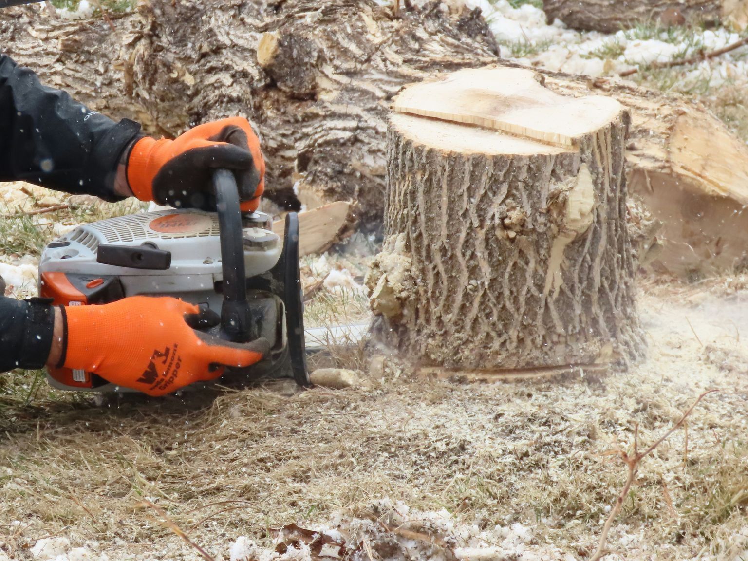 man in black jacket and blue denim jeans holding orange and black power tool